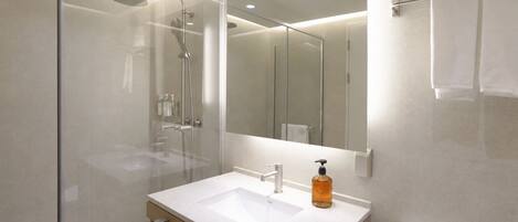 A modern bathroom with a glass shower enclosure, a sink with a soap dispenser, and a toilet.