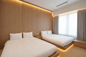 A hotel room with two beds, wooden panel walls, a window with curtains, and an air conditioning unit. - UH Suite The Jongno (Seoul)