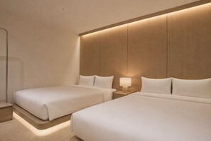 Une chambre d’hôtel avec deux lits, une table de chevet avec une lampe et une tête de lit en bois.