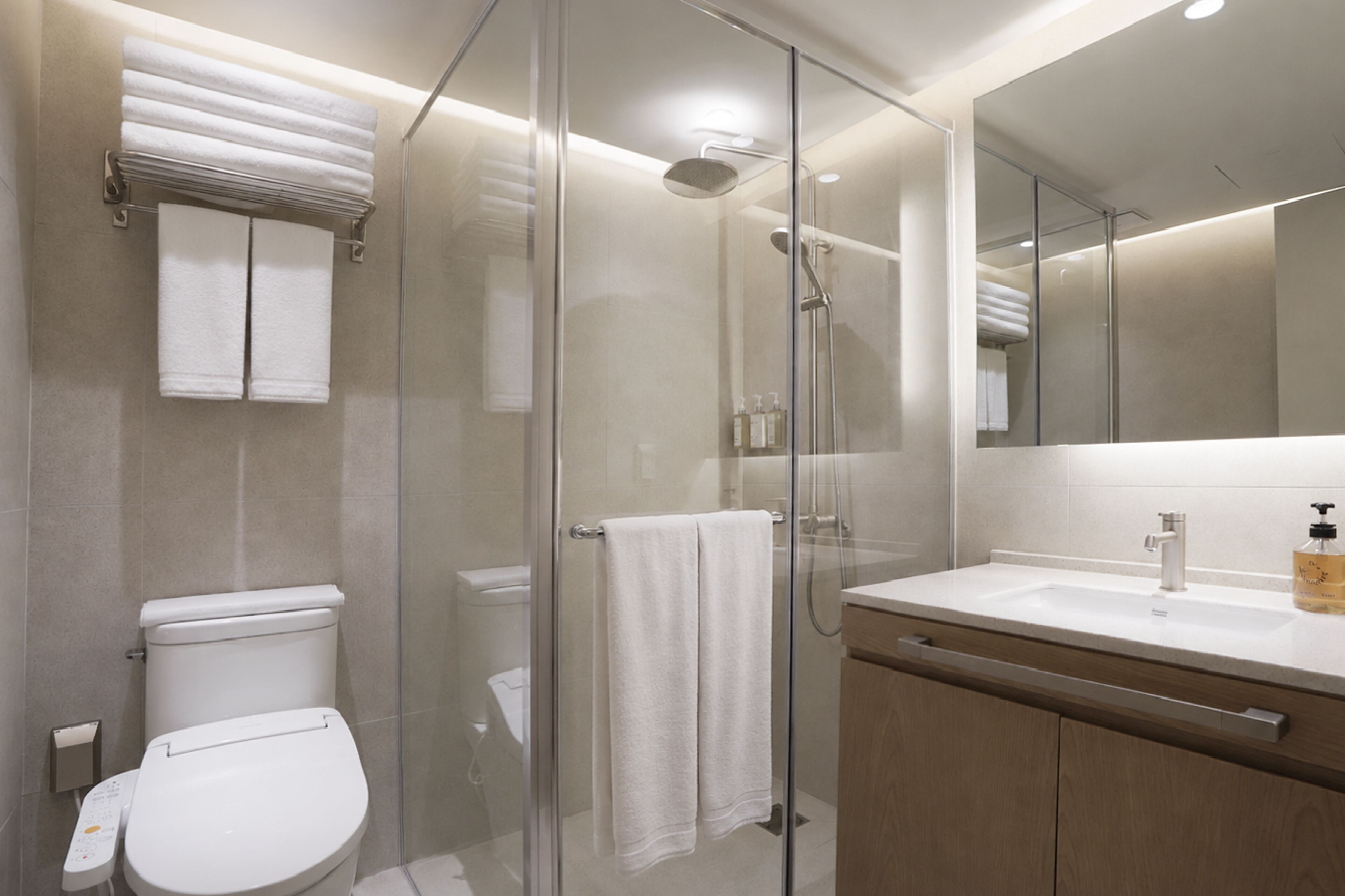 A modern bathroom with a glass-enclosed shower, a white toilet, a sink with a mirror, and a towel rack.