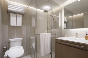 Une salle de bain moderne avec une douche à parois de verre, des toilettes blanches, un lavabo avec un miroir et un porte-serviettes.