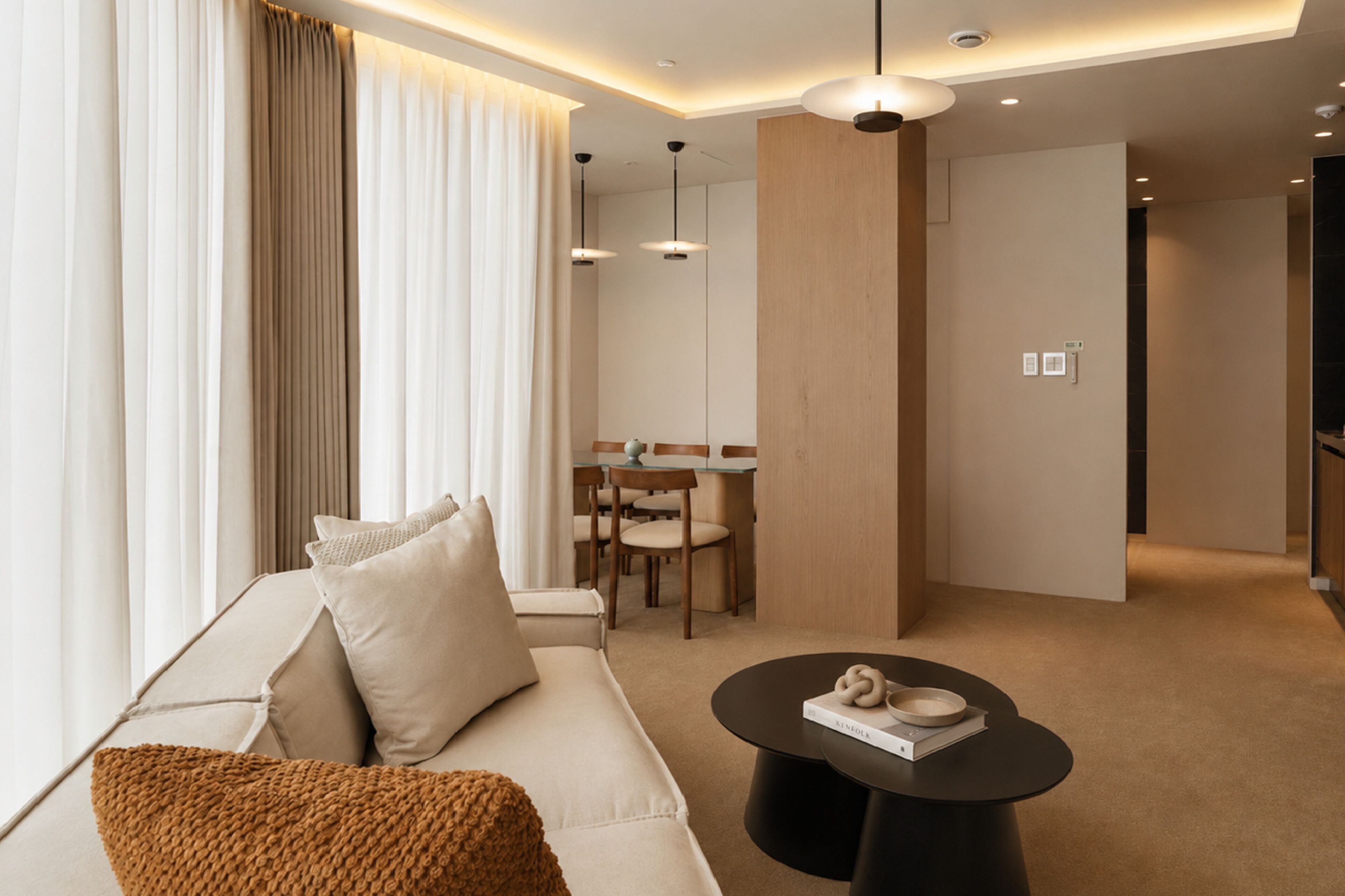 A modern hotel room with a sofa, a dining area, and a coffee table.