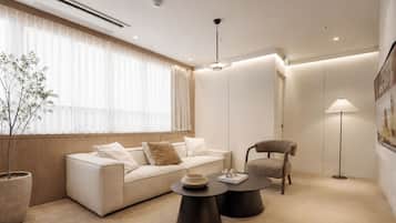 Una sala de estar moderna con un sofá, un sillón, una mesita de centro y una lámpara de pie.