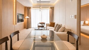 Habitación de hotel con mesa de comedor, sofá, cama y televisor.