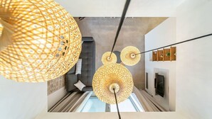Un interior moderno con un sofá, una chimenea y lámparas esféricas colgantes.
