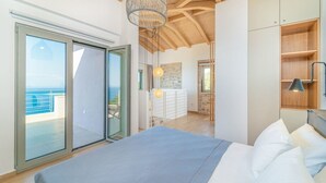 Un dormitorio con cama, armario y vista al mar a través de una puerta corredera.