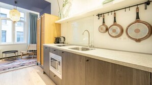 A modern kitchen with a large island, a built-in oven, and a hanging pot rack. - The Blue Parrot by SHWAY (Antwerp)