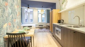 A modern kitchen with a wooden countertop, a built-in oven, and a sink. There is a dining area with a table and chairs. - The Blue Parrot by SHWAY (Antwerp)