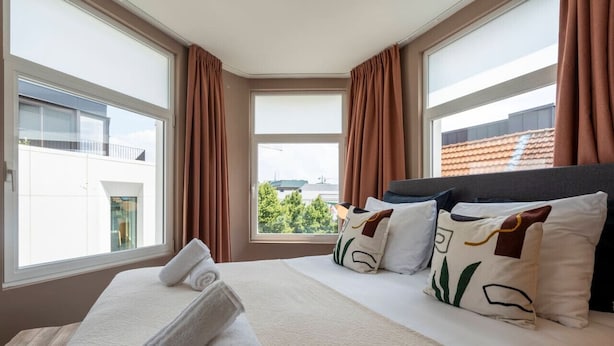 A hotel room with a large bed, two windows, and curtains. - The Suit by SHWAY Antwerp (Antwerpen)