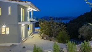 A modern two-story house with a balcony overlooking a body of water. - Villa Anticlea (Lefkada)