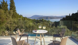 A terrace with a glass balustrade, a round table, and two chairs. - Villa Anticlea (Lefkada)