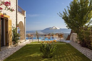 Zona de piscina con sillones reclinables y vistas al mar y a las montañas.