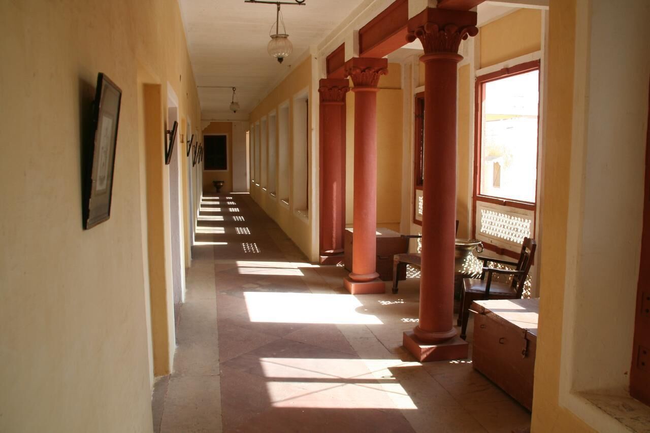 Un pasillo con columnas, un banco y una mesa.