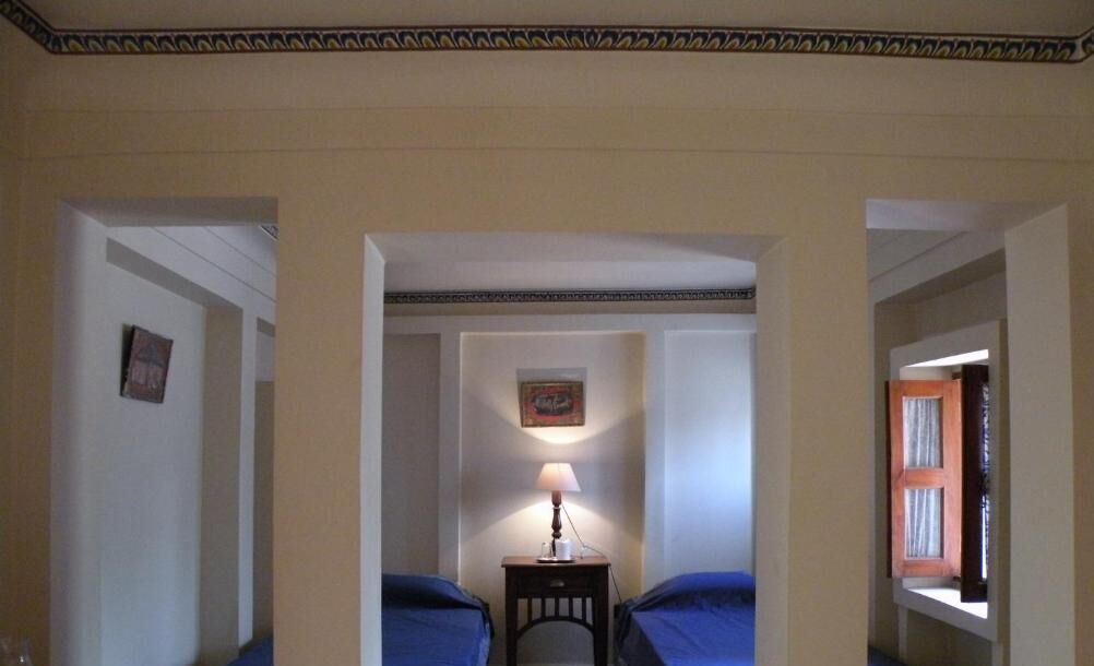 A narrow hallway with two beds on either side, a small table with a lamp, and a picture on the wall.