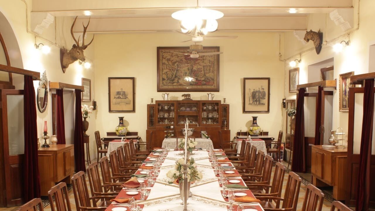 A formal dining room with a long table set for a meal, surrounded by wooden chairs.