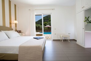 Une chambre d’hôtel avec un lit, une petite table, une chaise et une vue sur une piscine et des montagnes.