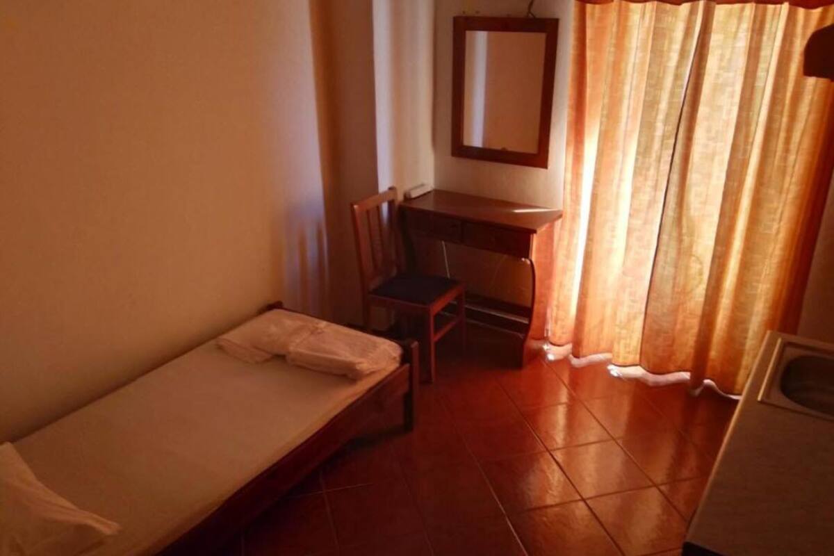 A small, compact room with a single bed, a desk, and a chair.