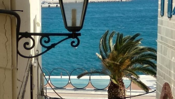 Un carrer estret amb una palmera i un fanal, que condueix a una vista de la costa.