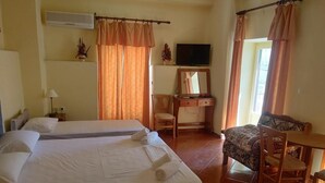 Habitació d'hotel amb dos llits, televisió, escriptori amb cadira i finestra amb cortines.