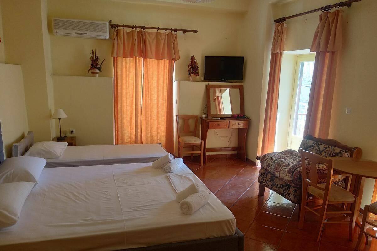 A hotel room with two beds, a TV, a desk with a chair, and a window with curtains.