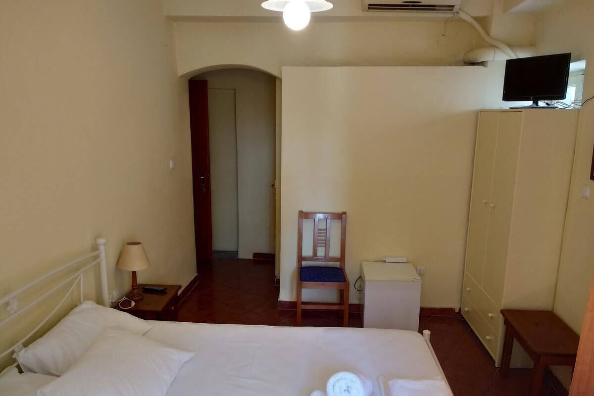 A hotel room with a bed, a chair, a desk, a wardrobe, and a television.