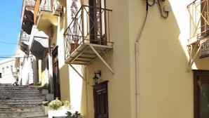 Un carrer estret amb escales de pedra que condueixen a un edifici groc, amb una porta fosca i un balcó.