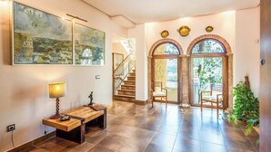 A spacious foyer with a staircase, a wooden bench, a lamp, and a large painting. - Mirador del Torcal Antequera by Ruralidays (Málaga)
