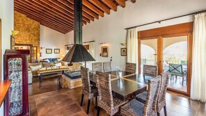 A dining area with wicker chairs, a dark wooden table, and a large pendant light.