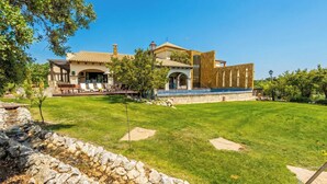 A large house with a patio, a stone wall, and a well-maintained lawn. - Mirador del Torcal Antequera by Ruralidays (Málaga)