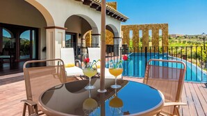 A poolside area with a table, chairs, and two cocktails. - Mirador del Torcal Antequera by Ruralidays (Málaga)