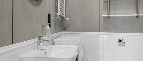 A modern bathroom with two sinks, a large mirror, and a towel rack.