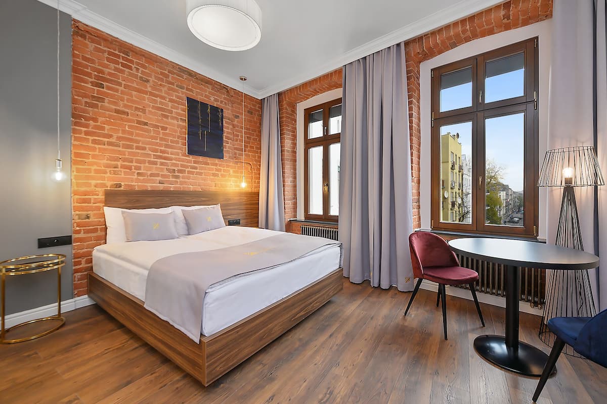 Ein Hotelzimmer mit Backsteinwand, einem großen Bett, einem runden Tisch und einem Stuhl.