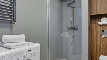 Ein modernes Badezimmer mit Duschkabine, integriertem Waschmaschine und Holzwaschtisch.