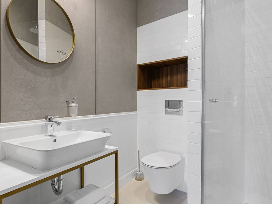 Ein modernes Badezimmer mit großem Spiegel, zwei Waschbecken, einer Duschkabine aus Glas und einem Holzregal.