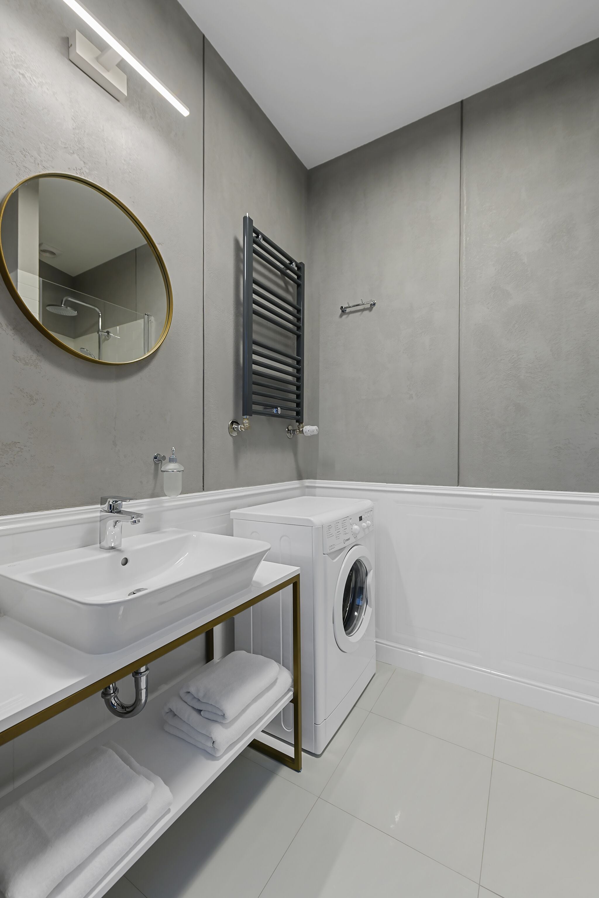 A modern bathroom with two sinks, a mirror, a towel rack, and a washing machine.