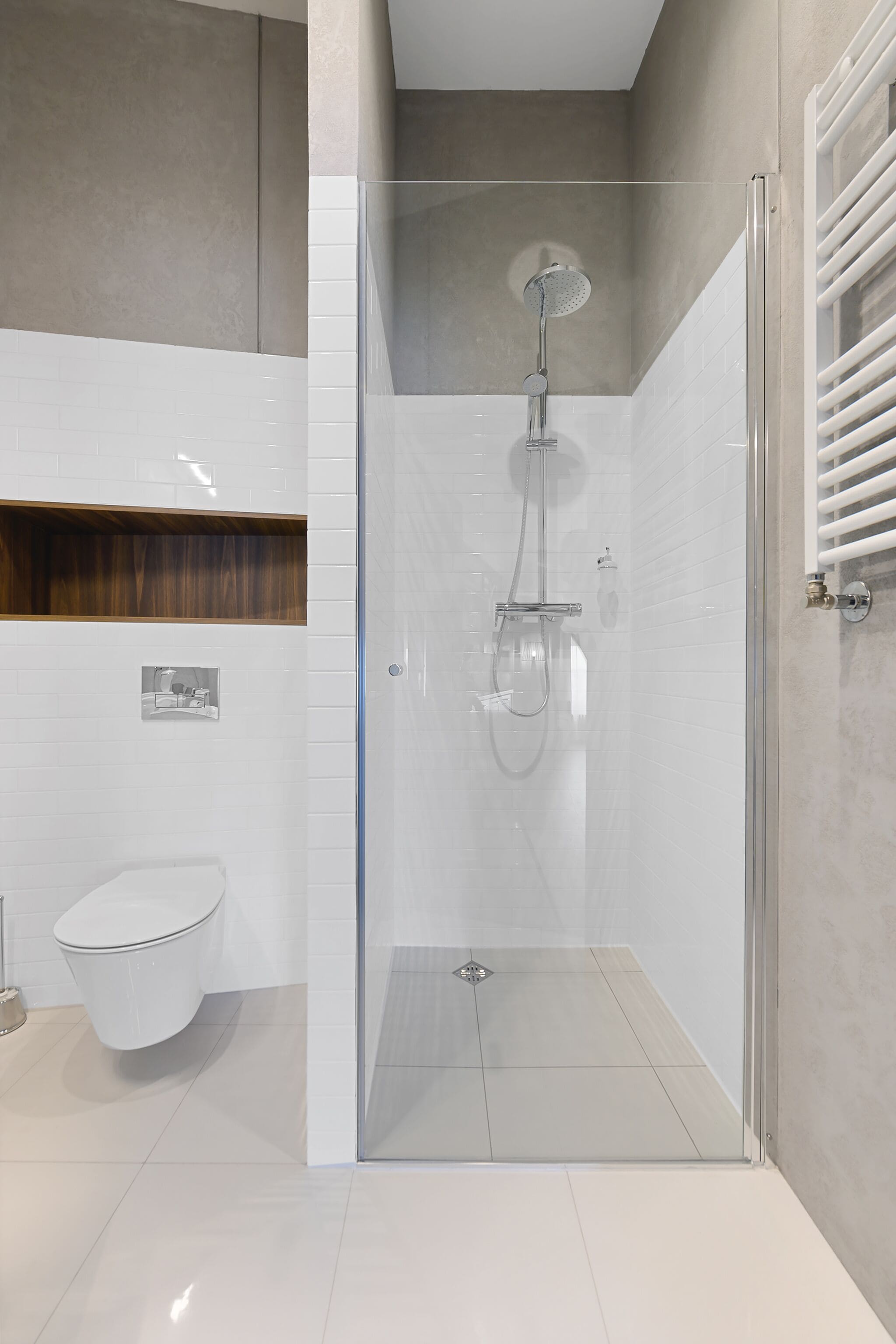 A modern bathroom with a glass-enclosed shower, a toilet, and a towel rack.