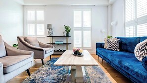 A living room with a blue sofa, two armchairs, a coffee table, and a bookshelf.