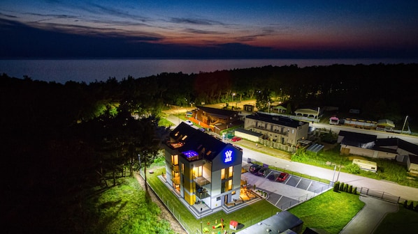 Un hôtel moderne doté d’une piscine sur le toit, d’un parking et offrant une vue sur la mer au crépuscule.