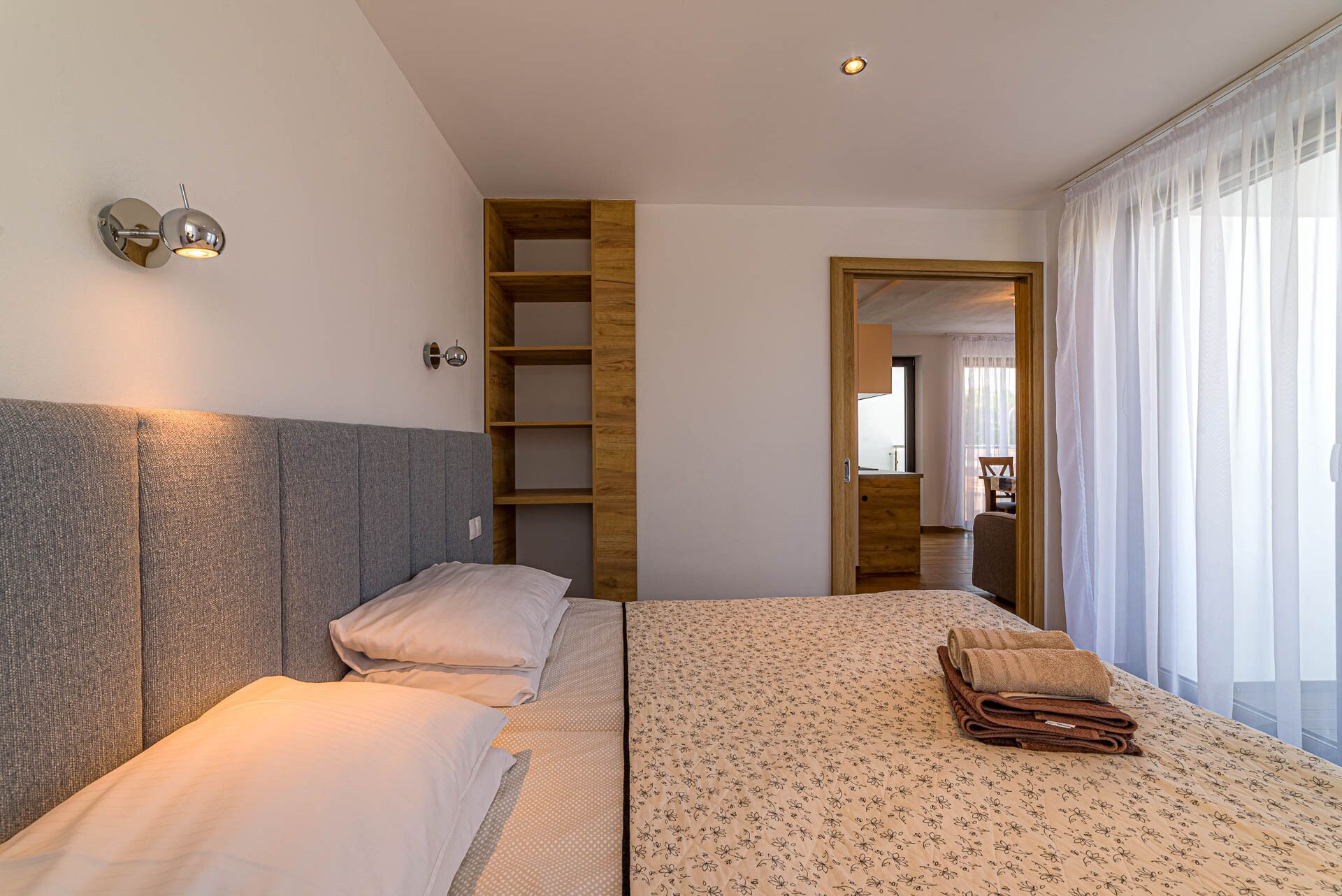 Une chambre à coucher comprenant un lit, une table de chevet, une armoire et une fenêtre avec des rideaux.