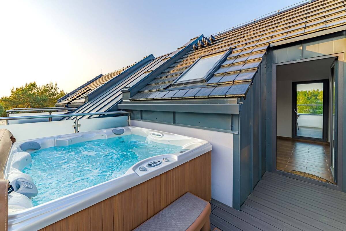 Un área moderna de hidromasaje al aire libre con terraza de madera y puerta de cristal que da a un balcón.