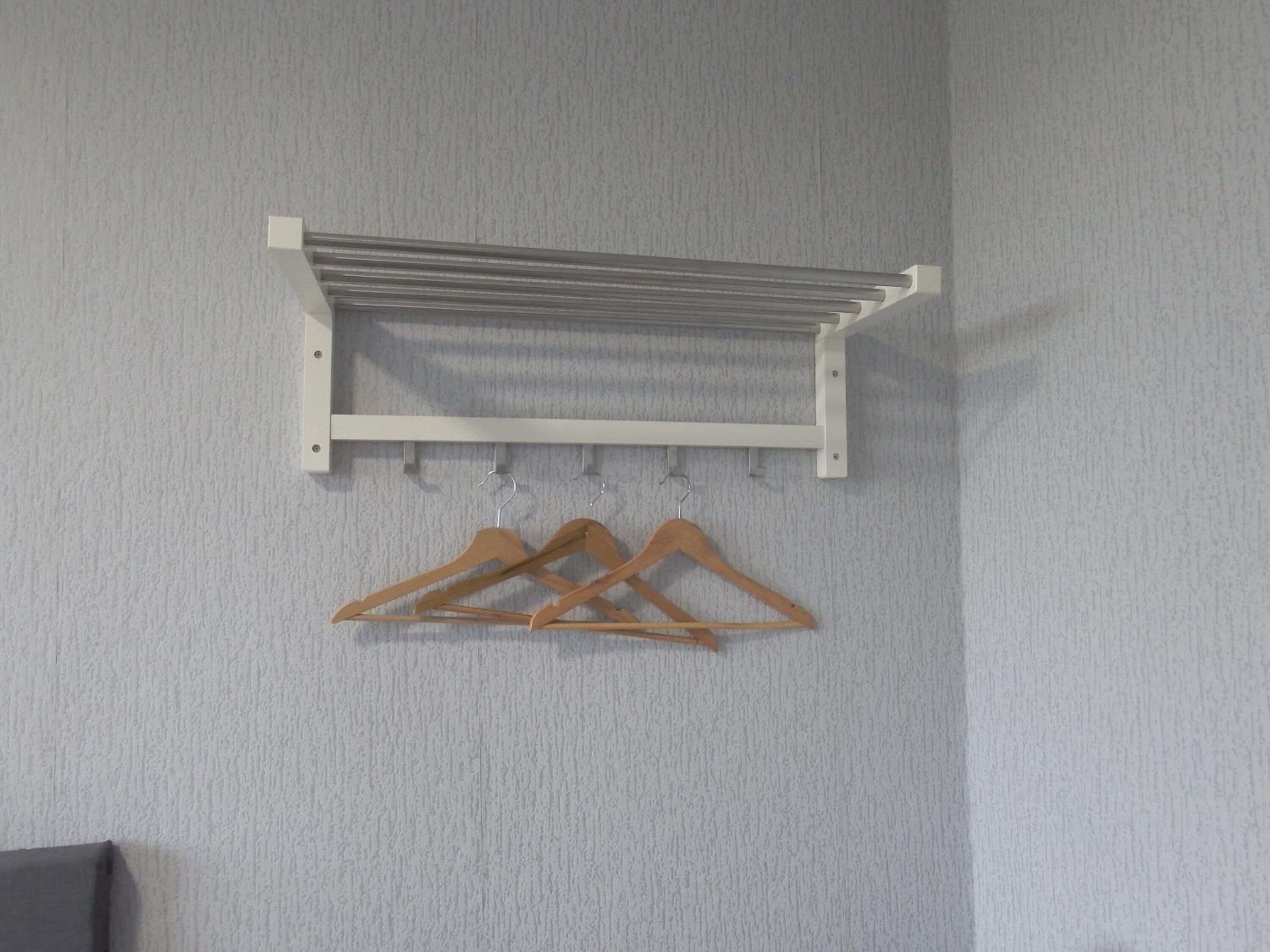 A wall-mounted drying rack with multiple hangers.