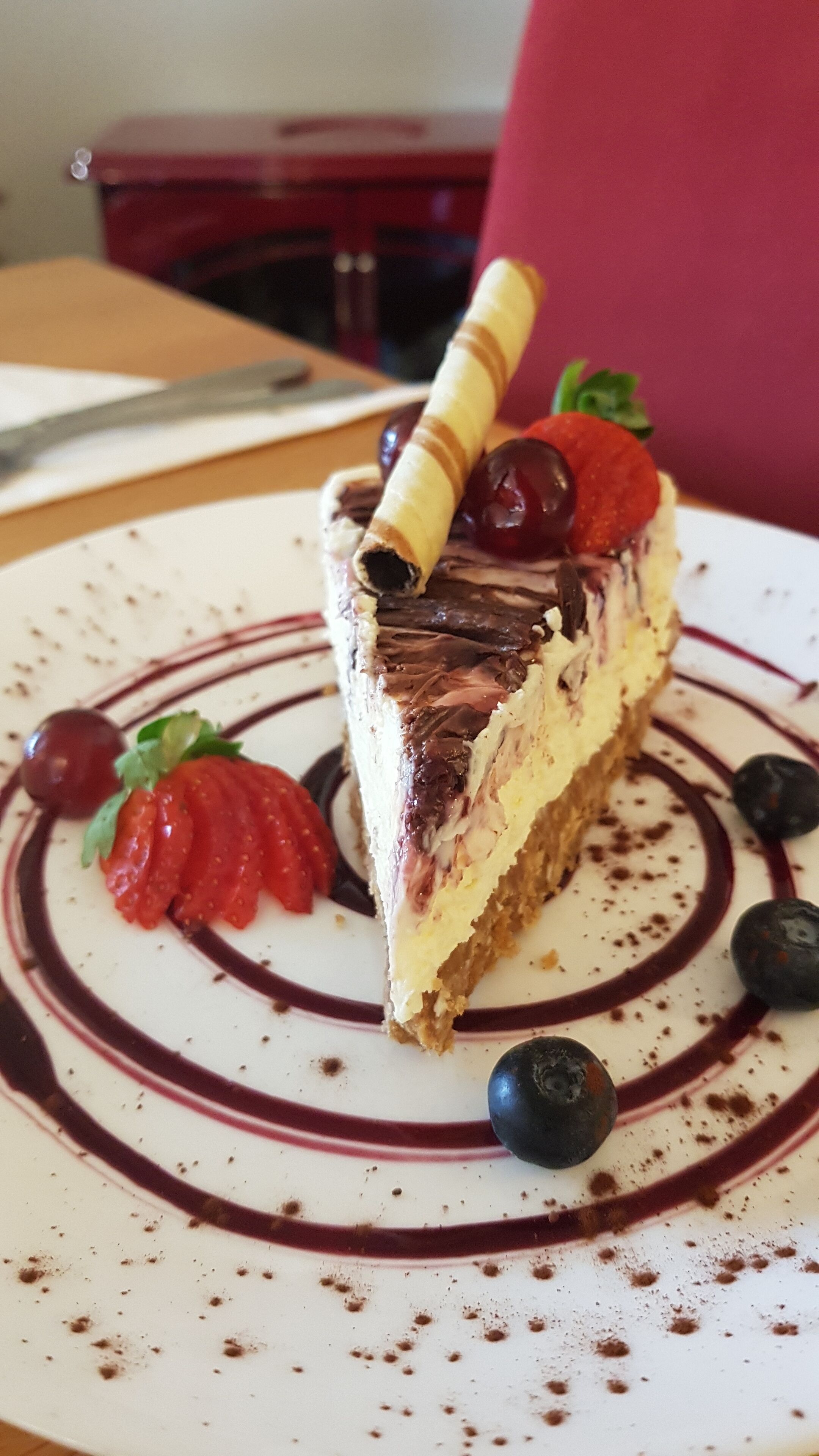 Una porción de pastel en capas con fresas y arándanos sobre un plato.