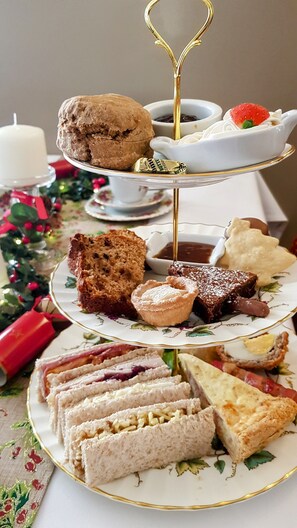 A tiered dessert stand with various pastries and a candle in the background. - The Haven Inn (Barrow upon Humber)