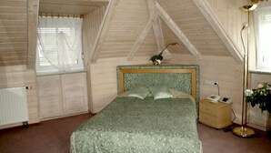 A bedroom with a bed, a bedside table, a lamp, and a window with curtains. - Gästehaus Villa Sulmana (Neckarsulm)