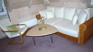 A cozy room with a white sofa, a green chair, and a small round table with a vase of flowers. - Gästehaus Villa Sulmana (Neckarsulm)