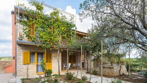 A two-story building with a stone facade, yellow shutters, and a balcony with vines. - 3 bedroom gorgeous apartment in Skradin (Skradin)