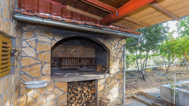 A stone-built outdoor kitchen with a built-in grill, a fire pit, and a stack of firewood. - 3 bedroom gorgeous apartment in Skradin (Skradin)