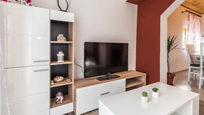 A modern living room with a flat-screen TV, white cabinetry, and a small table with potted plants. - 3 bedroom gorgeous apartment in Skradin (Skradin)
