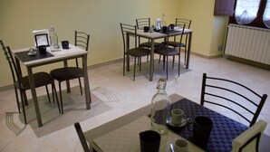 Een eethoek met twee tafels, elk voorzien van vier stoelen. Op de tafels staan verschillende zwarte bekers en een fles.
