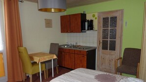 Een compacte slaapkamer met een bed, een klein kitchenette en een eethoek.
